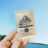 Stowaway instant coffee packet held against a blue sky background