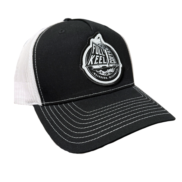 A light blue and navy trucker hat with white mesh back panels. The front panel features a circular embroidered patch with a sailboat design and the text 'FULL KEEL COFFEE'.